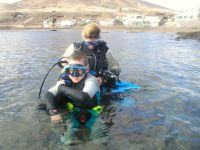 Helping a daycourse student into equipment in the water