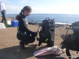 A Junior PADI diver prepares and checks her own equipment before a dive in Gran Canaria